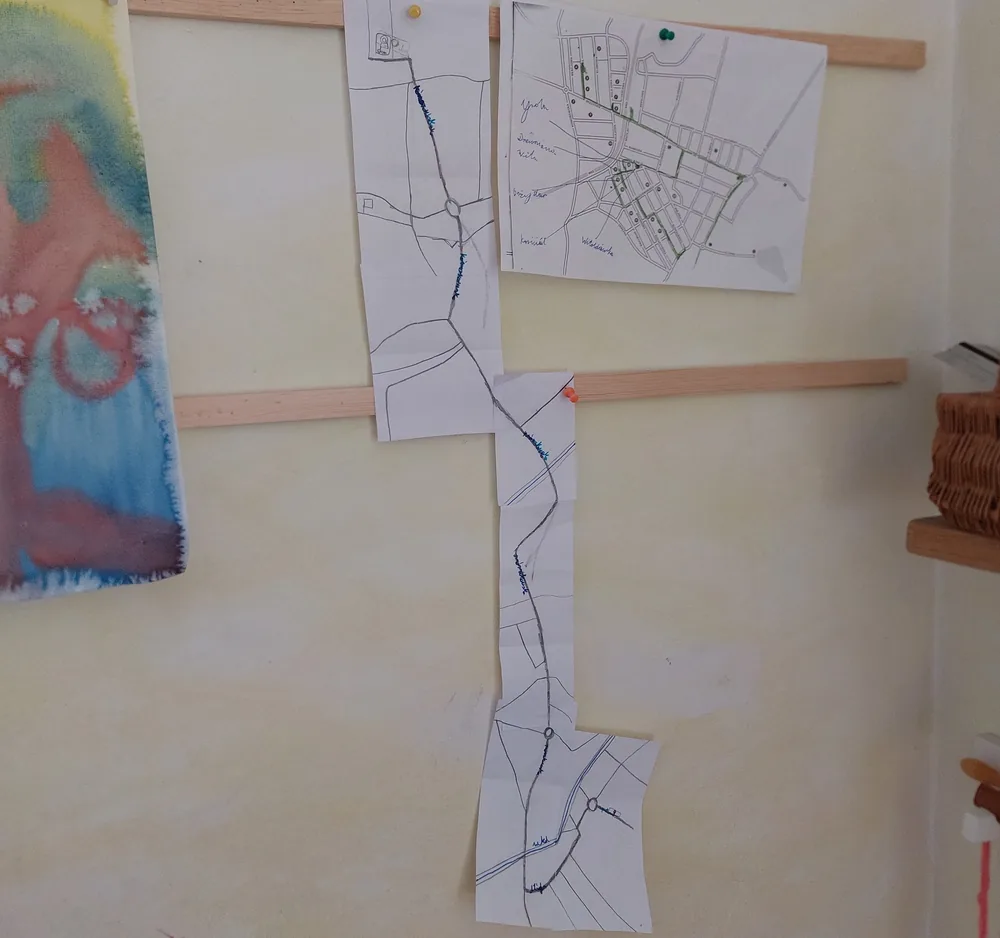 Ręcznie narysowane mapy okolicy — mapa drogi i plan miejscowości — powieszone na ścianie